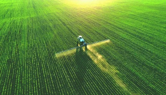 Drone view of a tractor spraying a green field, illustrating USDA's SCION government IT modernization project