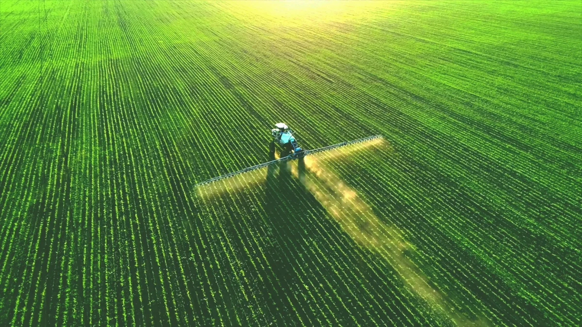 Drone view of a tractor spraying a green field, illustrating USDA's SCION government IT modernization project