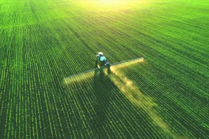 Drone view of a tractor spraying a green field, illustrating USDA's SCION government IT modernization project