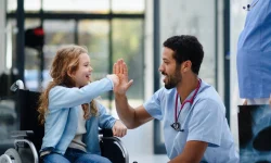 Physician high-fiving a young patient in a wheelchair, the kind of patient relationships that help rural healthcare attract and keep providers