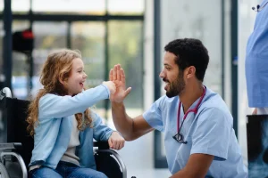 Physician high-fiving a young patient in a wheelchair, the kind of patient relationships that help rural healthcare attract and keep providers