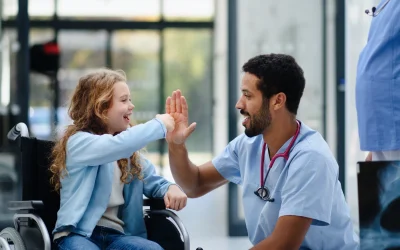 Physician high-fiving a young patient in a wheelchair, the kind of patient relationships that help rural healthcare attract and keep providers