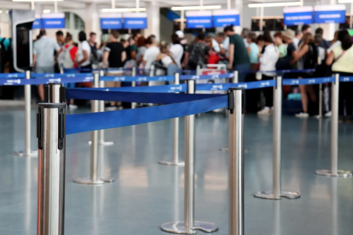 Travelers wait in a roped queue at an airport check-in area, the kind of friction government CX projects aim to reduce