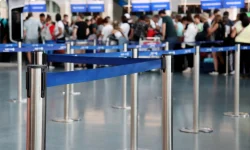 Travelers wait in a roped queue at an airport check-in area, the kind of friction government CX projects aim to reduce