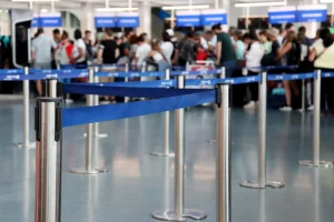 Travelers wait in a roped queue at an airport check-in area, the kind of friction government CX projects aim to reduce