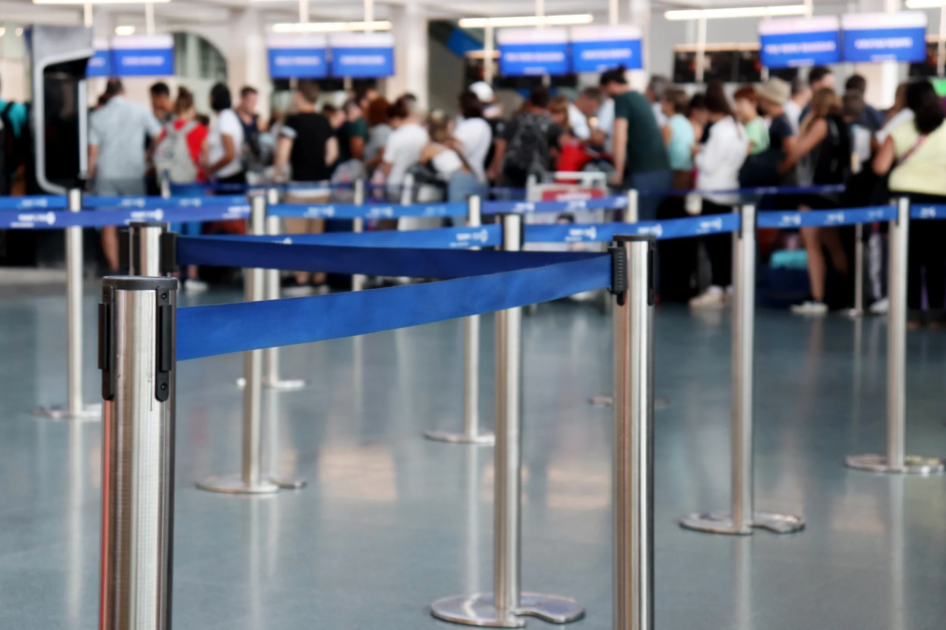 Travelers wait in a roped queue at an airport check-in area, the kind of friction government CX projects aim to reduce
